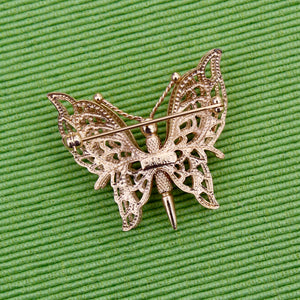 Gold butterfly brooch on a green textured background