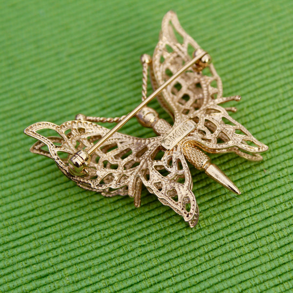 Gold butterfly brooch on a green textured background